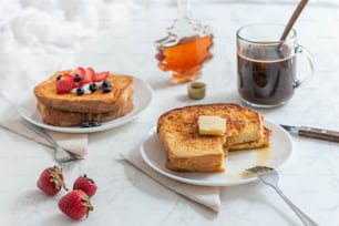 two plates of french toast with butter and strawberries