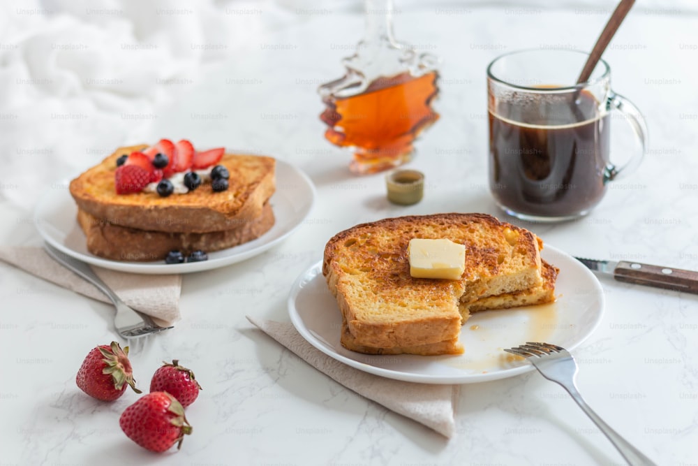 two plates of french toast with butter and strawberries