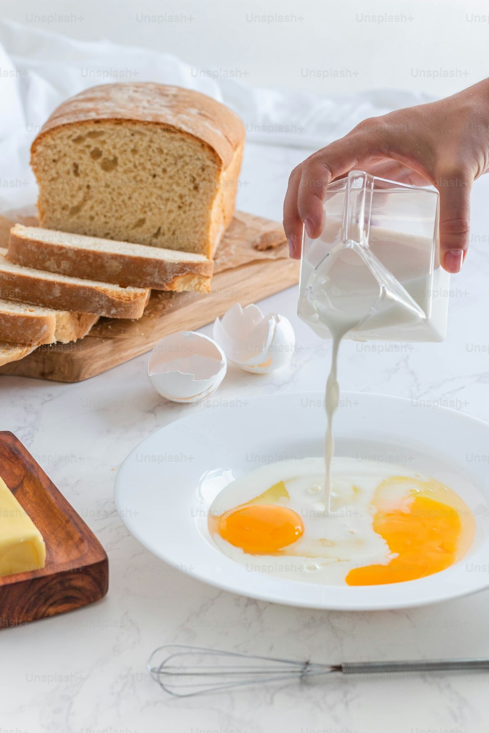 una persona vertiendo leche en un tazón de huevos