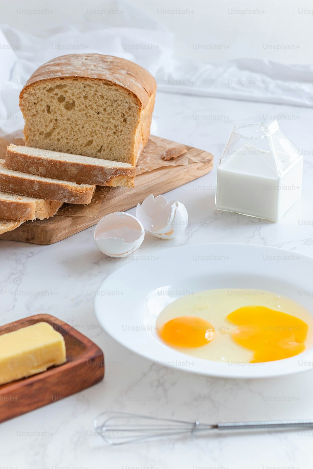a white plate topped with eggs next to a loaf of bread