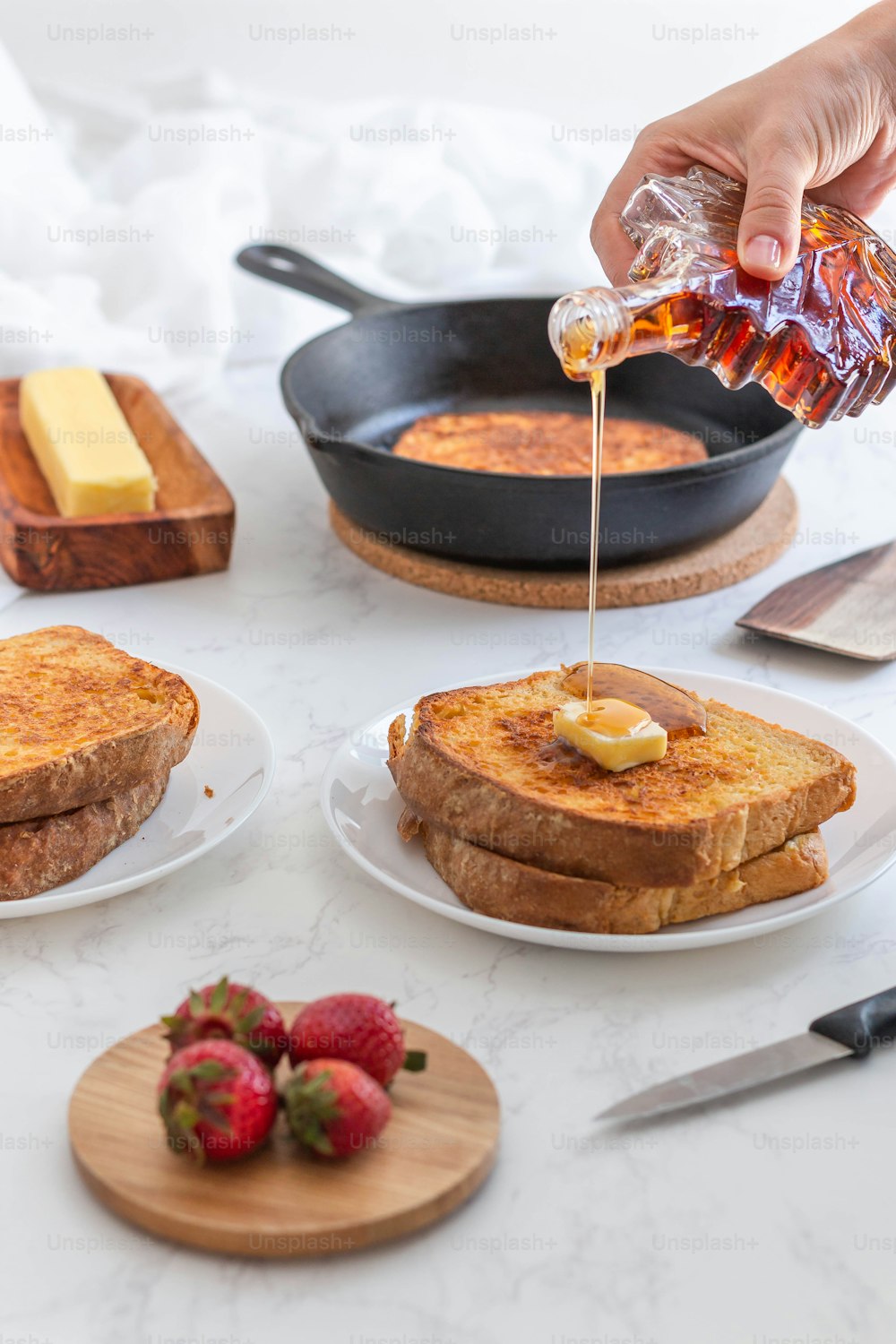 a person pouring syrup on some french toast