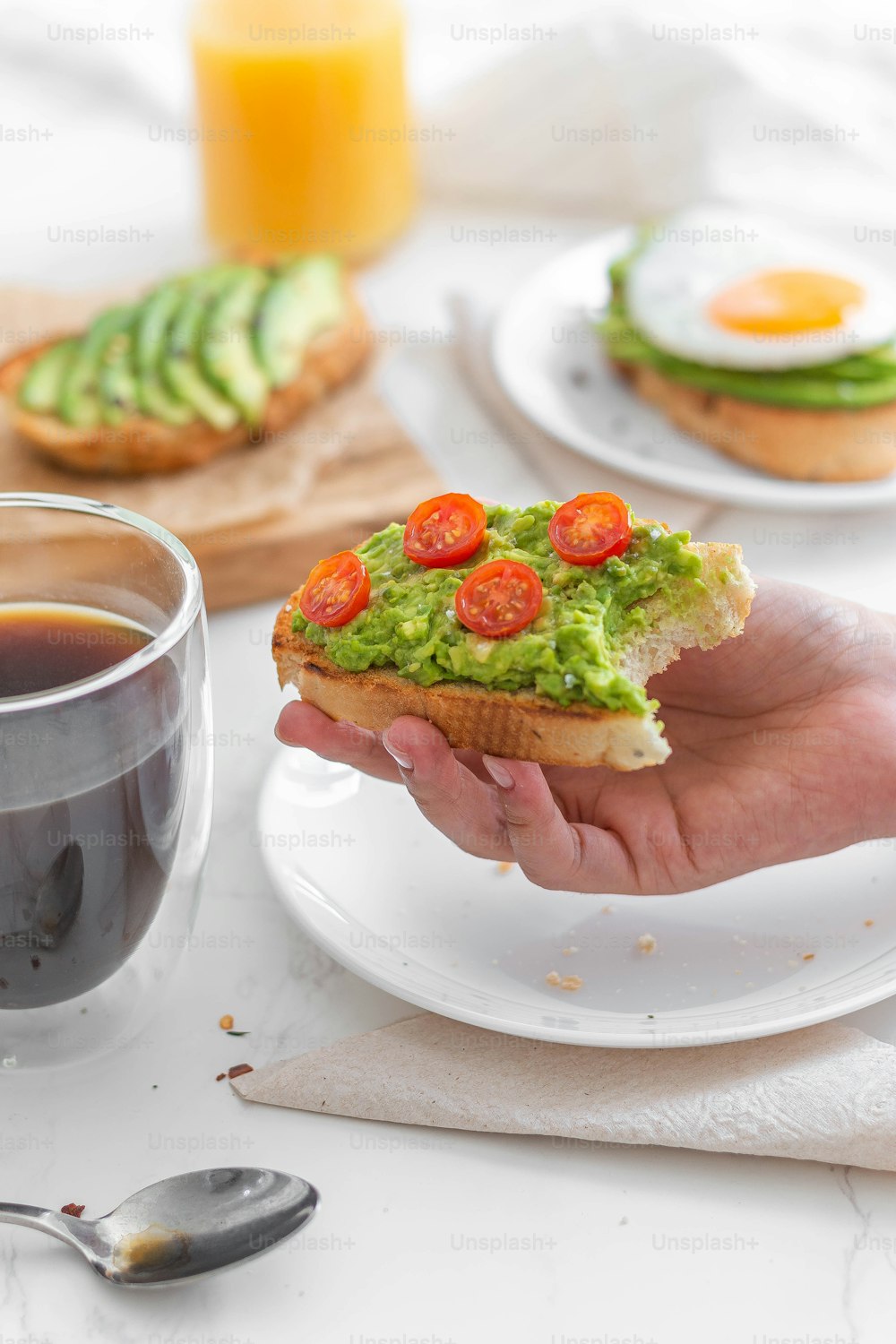 a person holding a piece of bread with guacamole and tomatoes on it