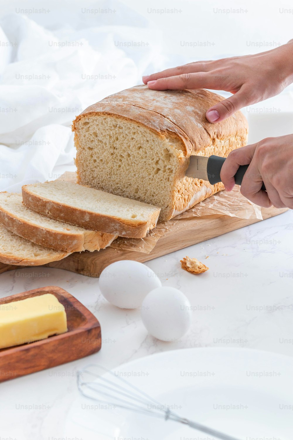 a person cutting a loaf of bread on a cutting board