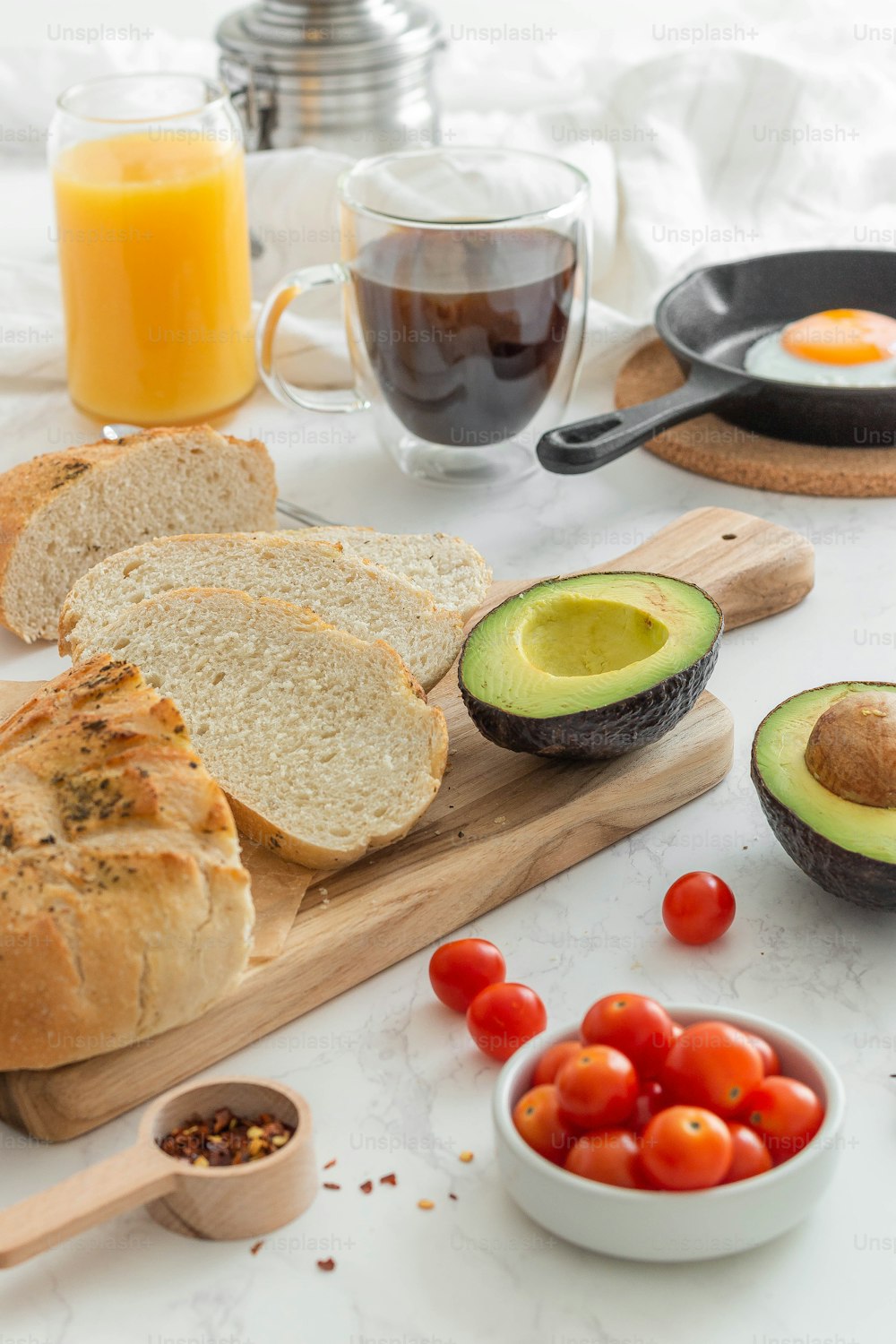 a table with bread, tomatoes, avocado, and other foods