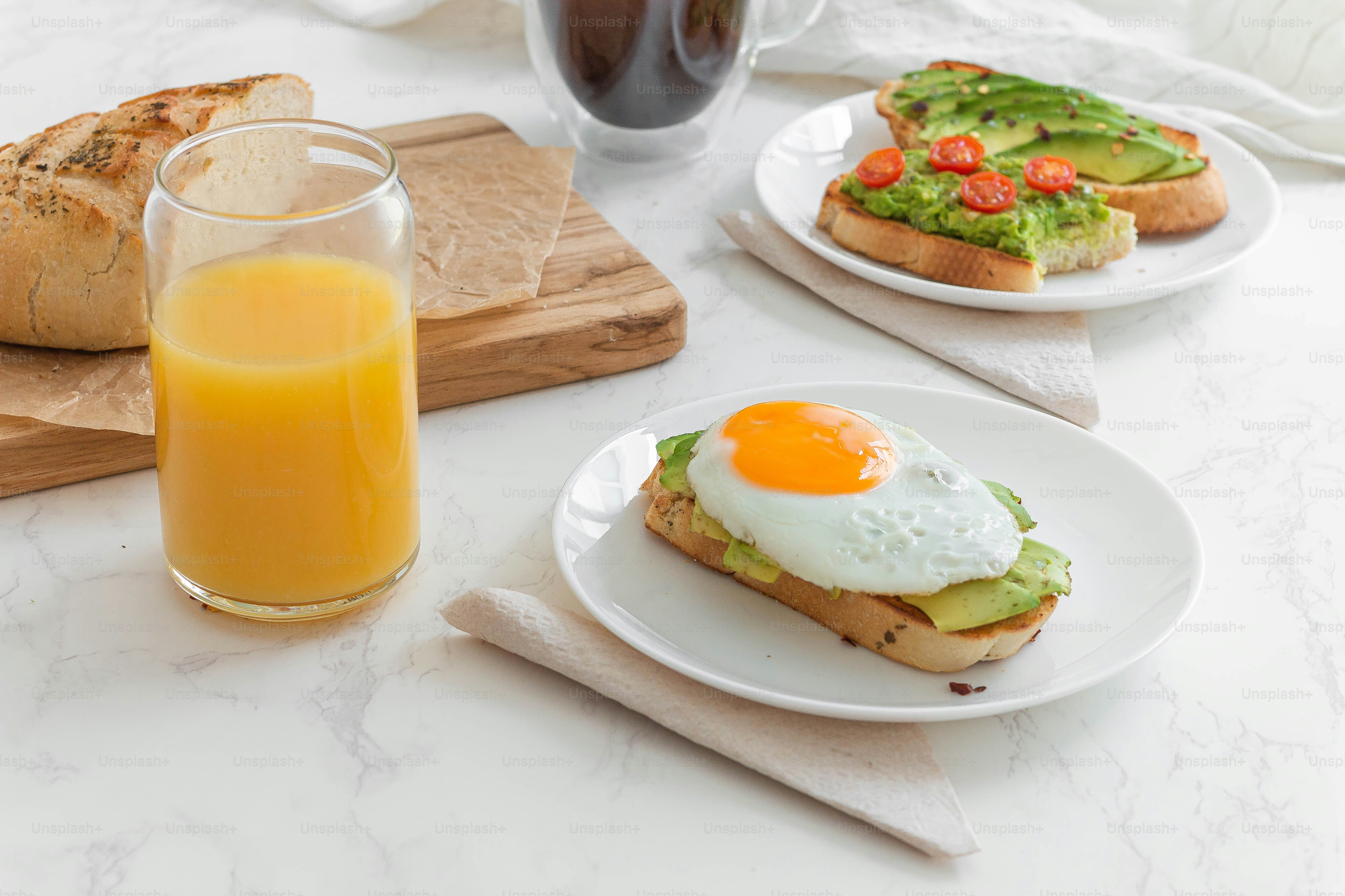 a table topped with plates of food and a glass of orange juice