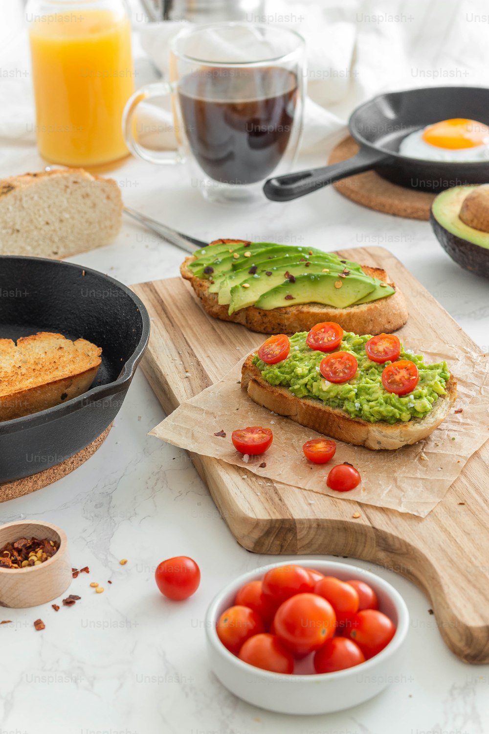 a table topped with bread, tomatoes and avocado