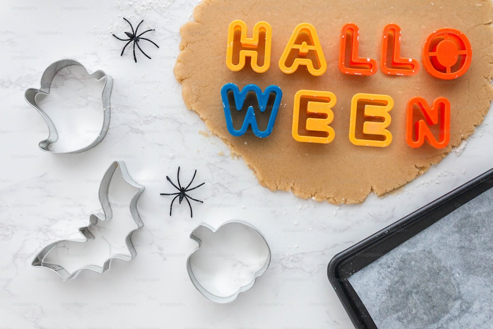 Una galleta con la palabra Halloween escrita junto a los cortadores de galletas