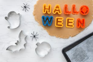 a cookie with the word halloween spelled out next to cookie cutters