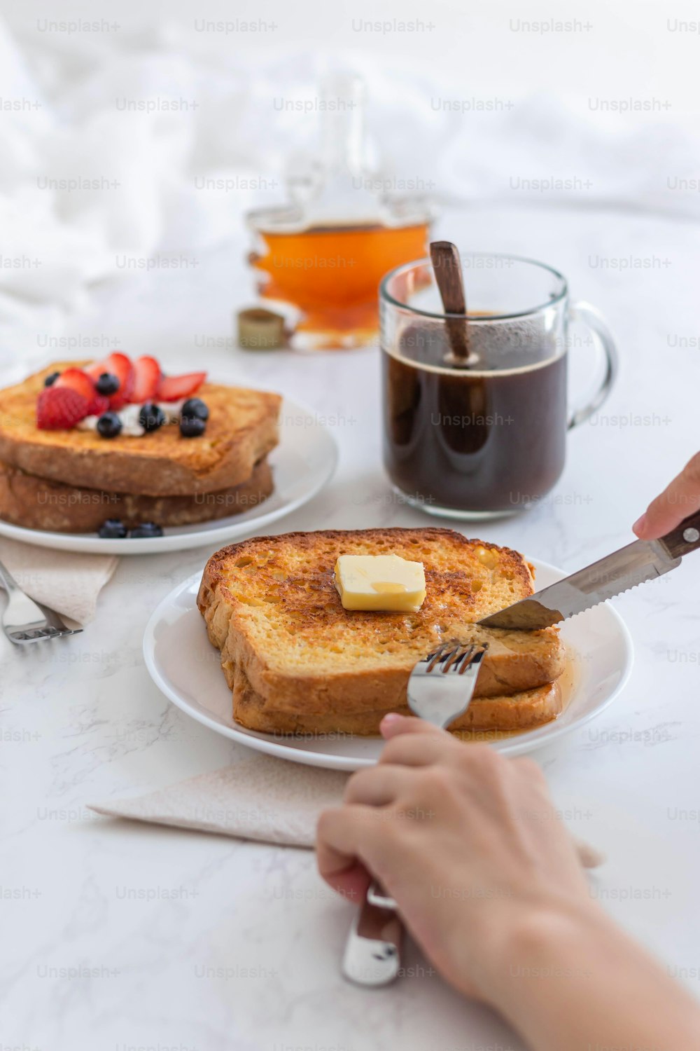 a person cutting a piece of french toast with a knife and fork