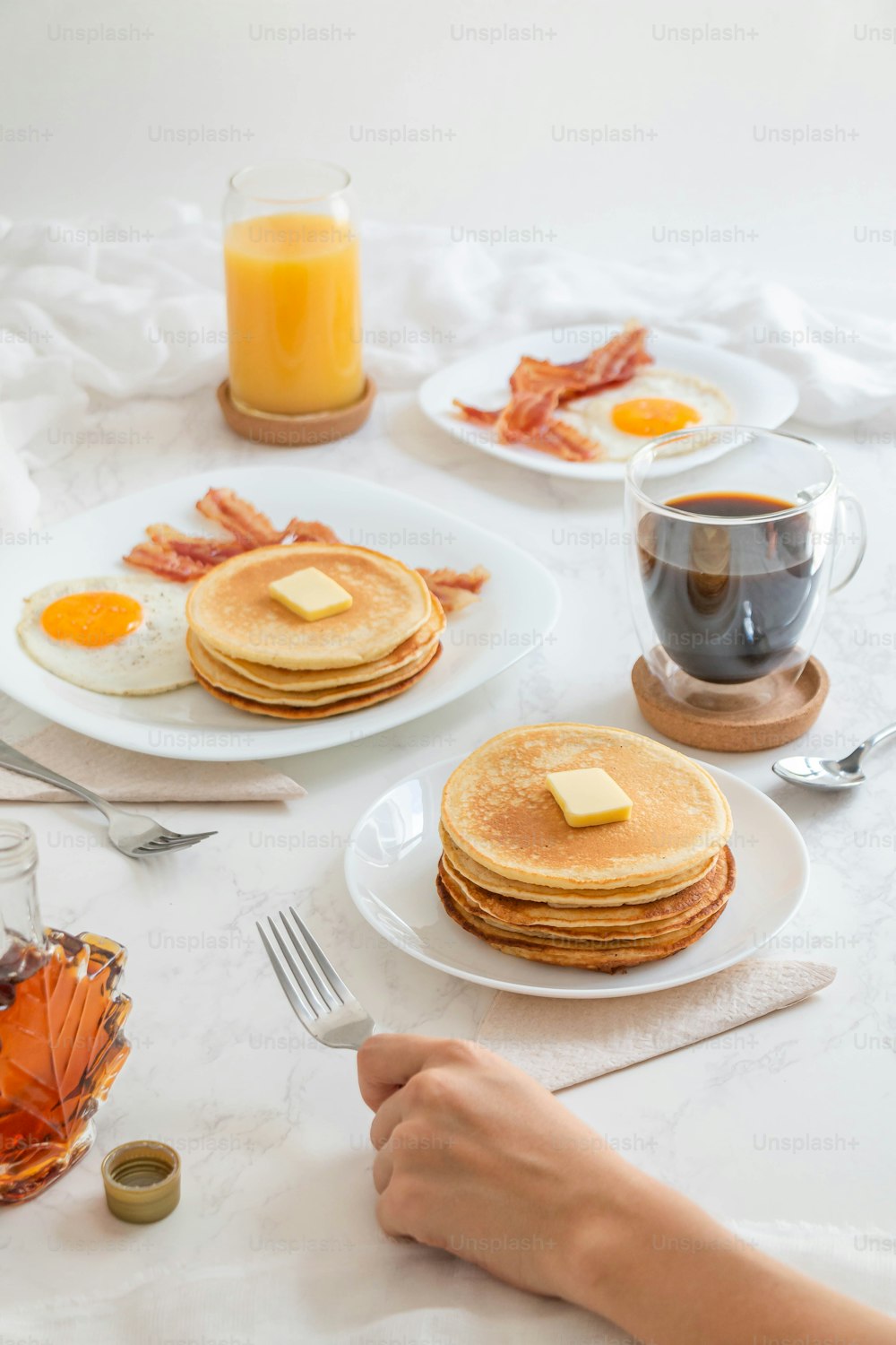 a table topped with pancakes and bacon next to a cup of coffee