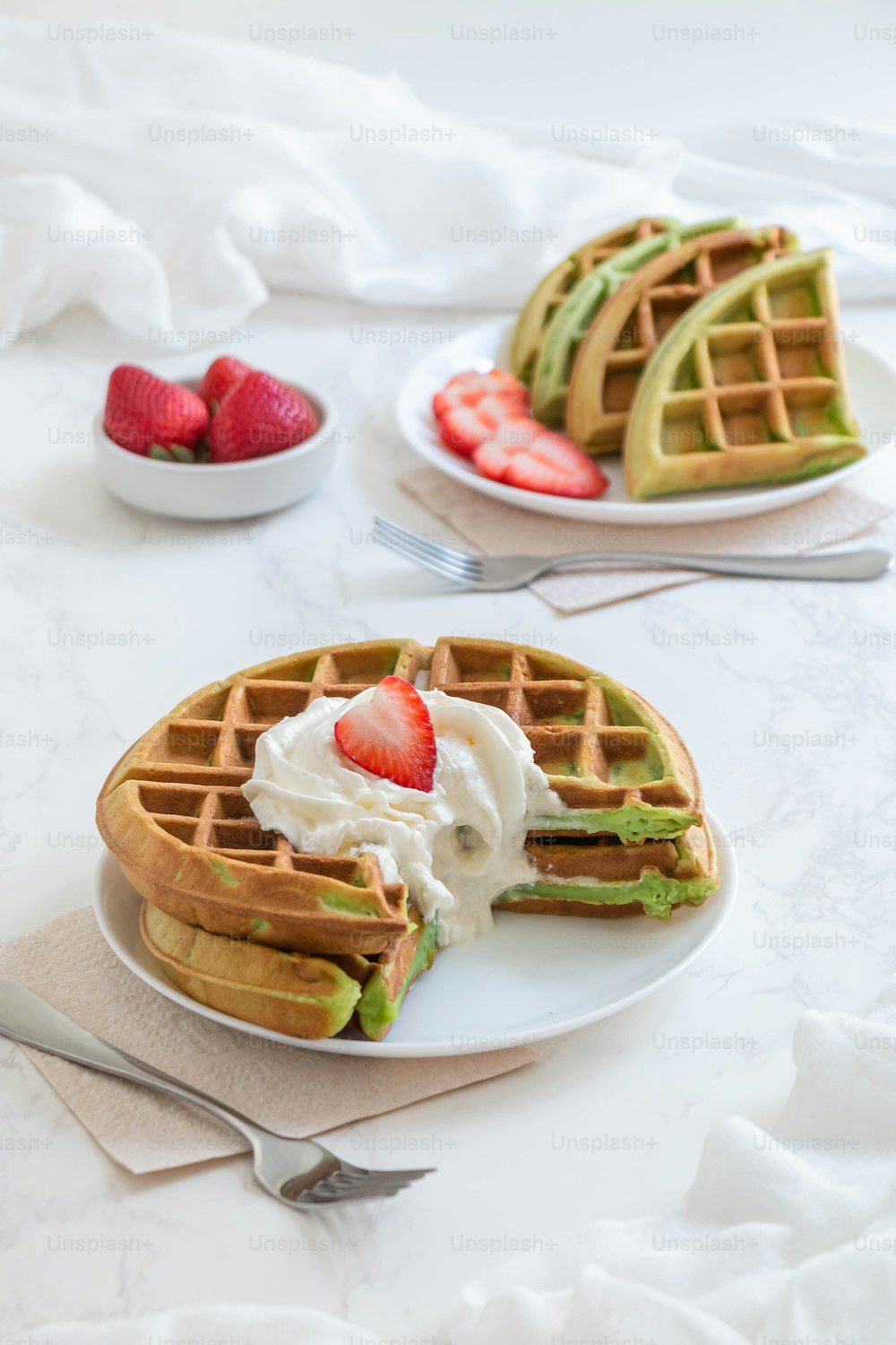 a plate of waffles with whipped cream and strawberries