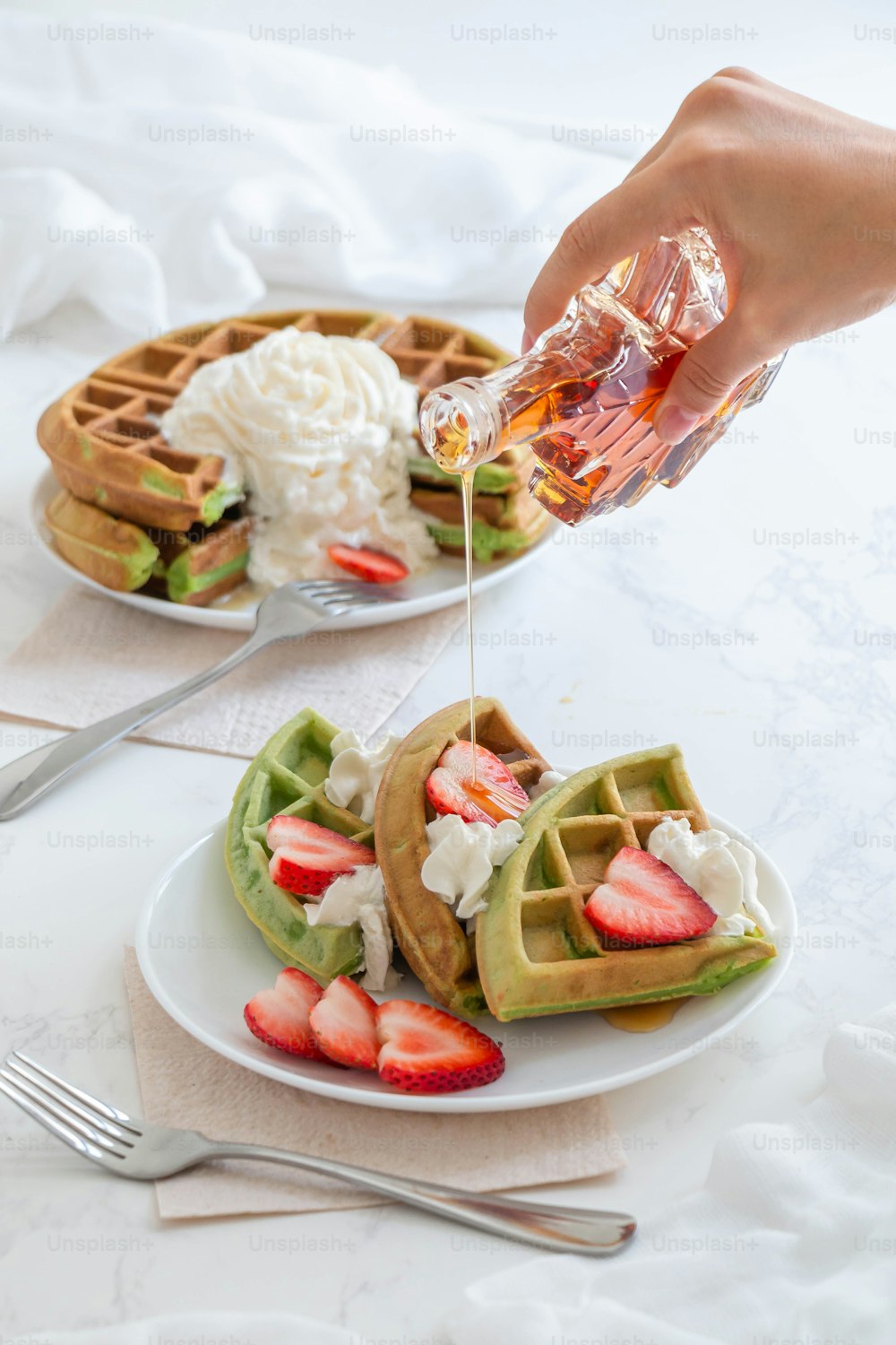 a person pouring syrup on a plate of waffles