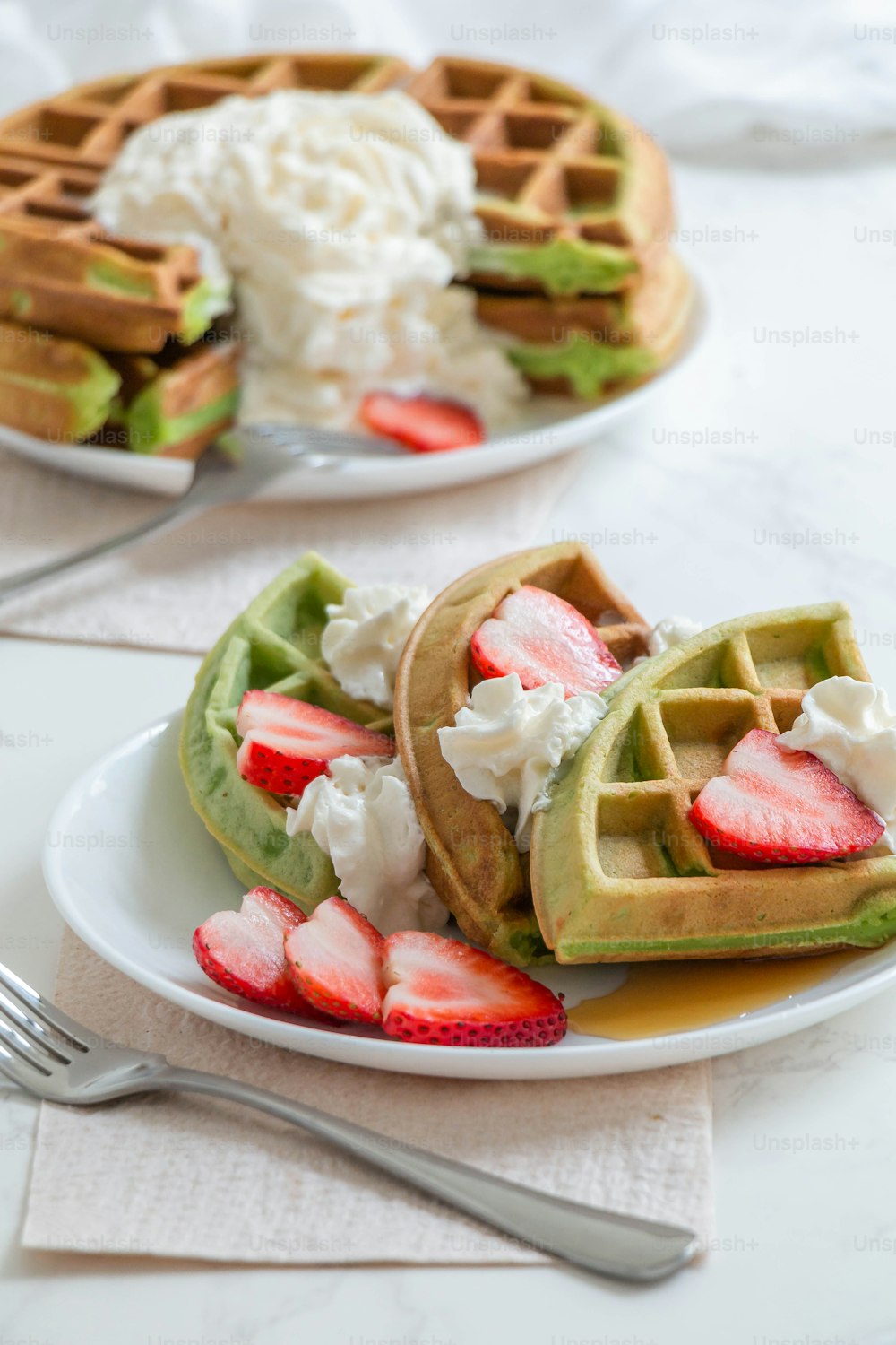a plate of waffles with strawberries and whipped cream