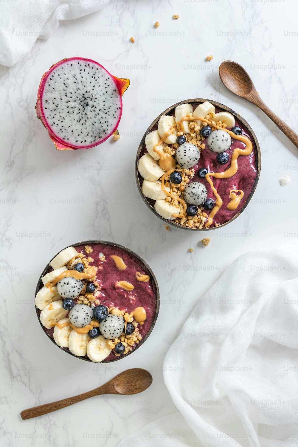 two bowls filled with fruit and nuts next to a spoon