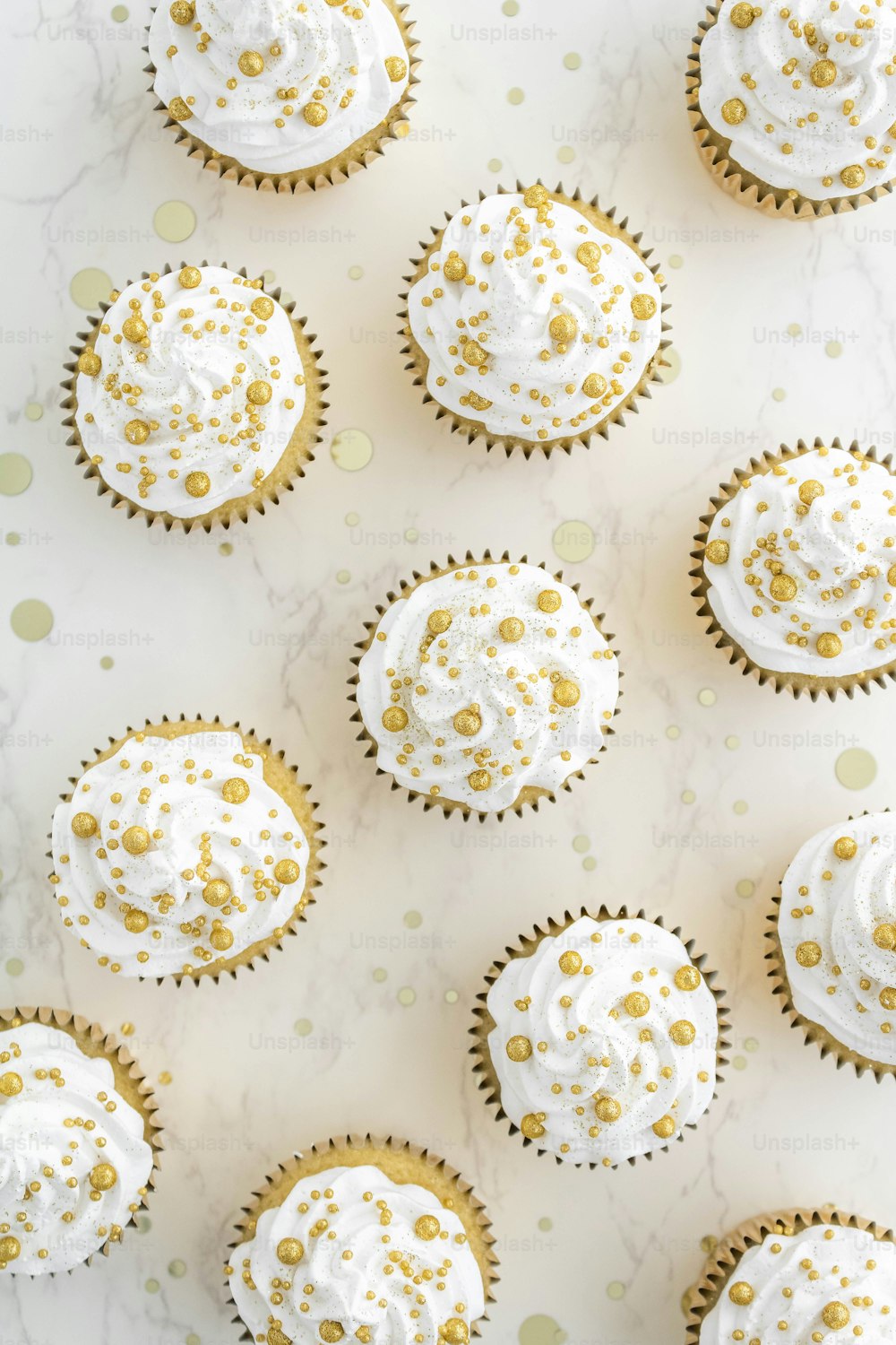 cupcakes with white frosting and gold sprinkles