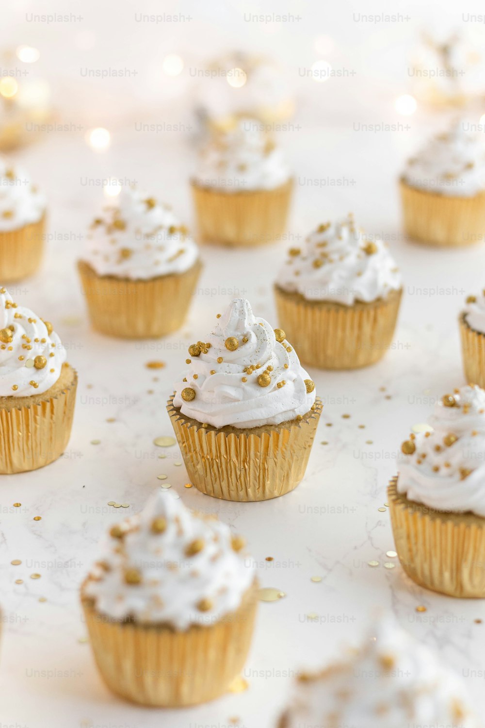 cupcakes with white frosting and gold sprinkles