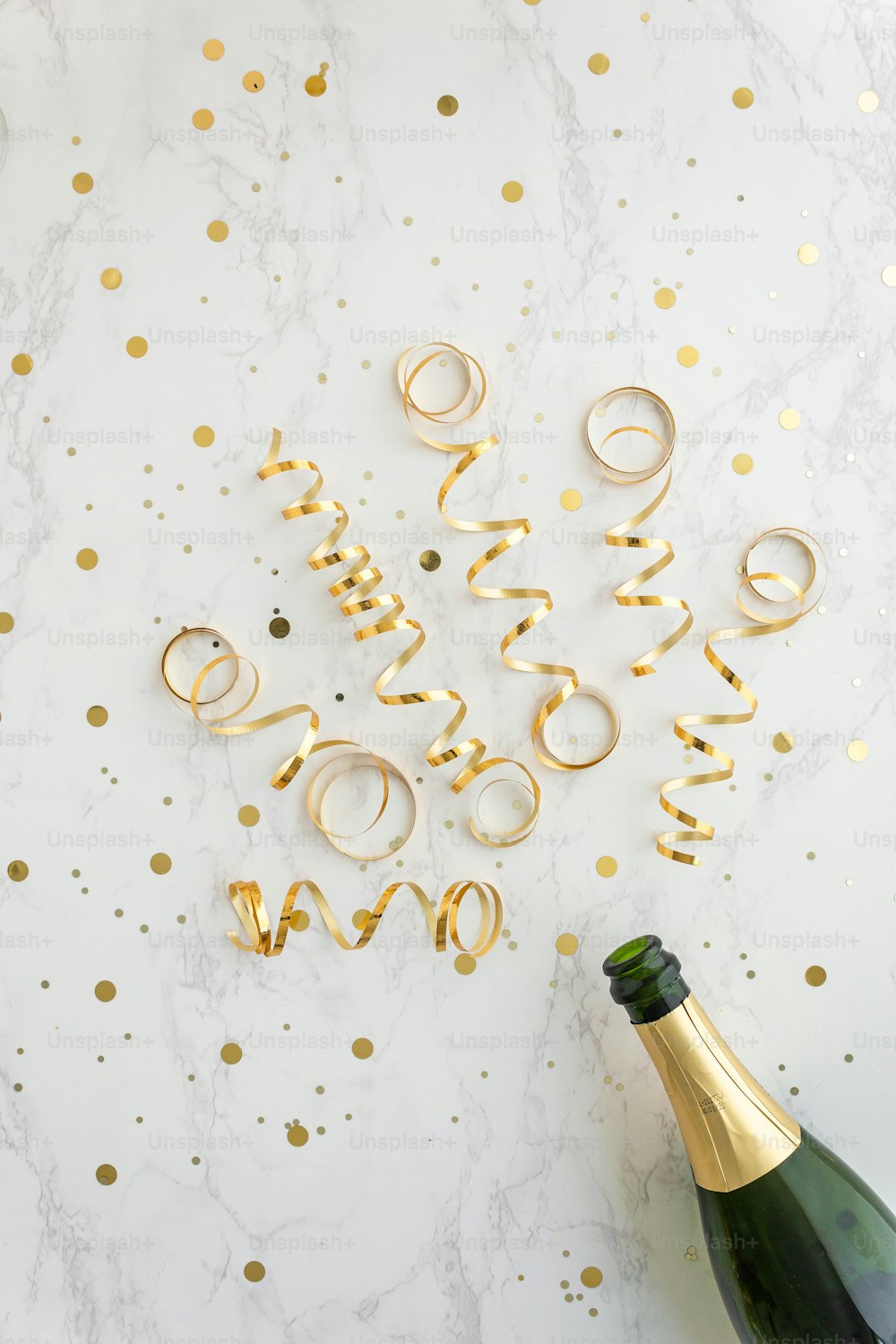 uma garrafa de champanhe e alguns confetes de ouro