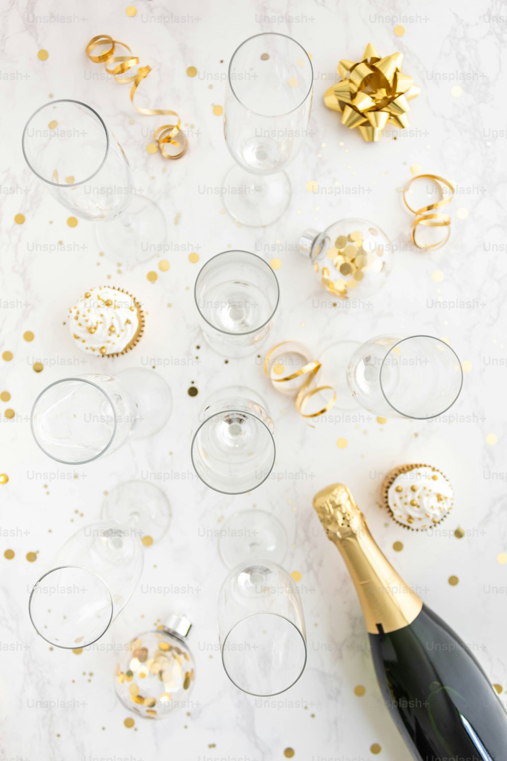 Una botella de champán sentada junto a un montón de copas