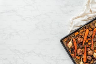 a tray of roasted carrots and potatoes on a marble surface