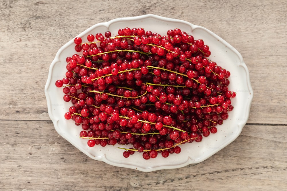 a white bowl filled with red berries on top of a wooden table