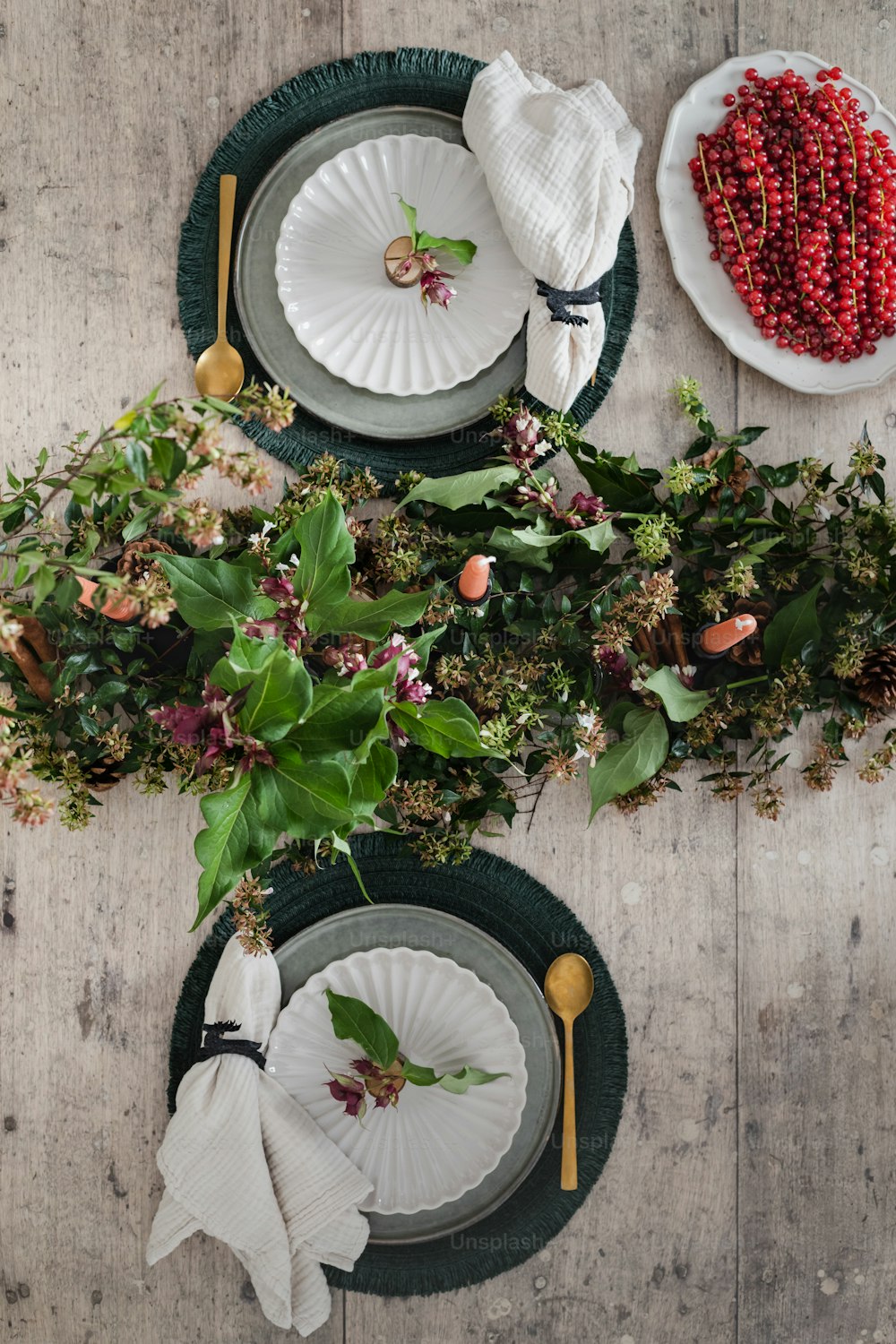 una mesa cubierta con platos y flores encima de una mesa de madera