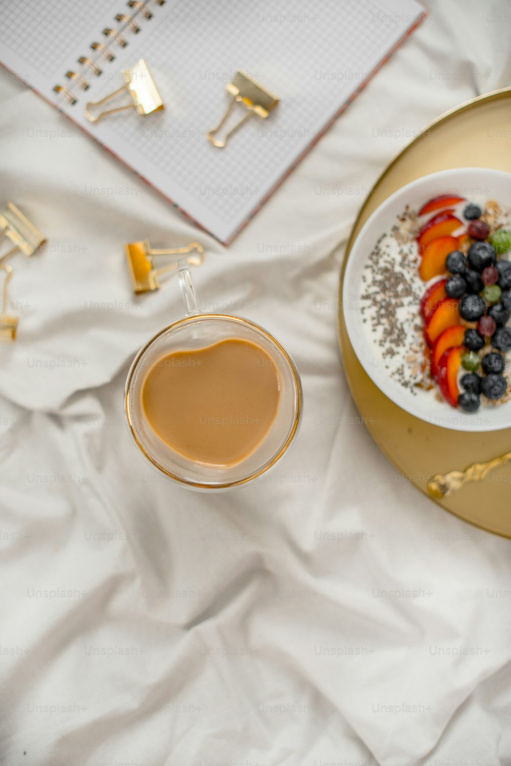 a bowl of fruit and a plate of food on a bed