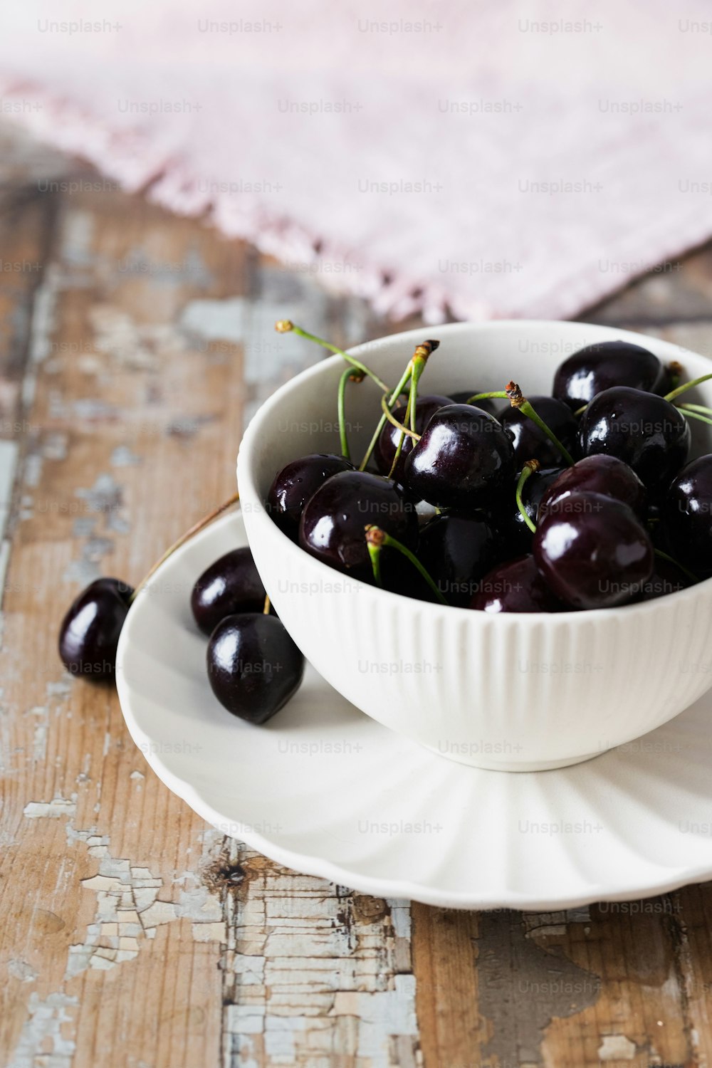 a white bowl filled with cherries on top of a wooden table