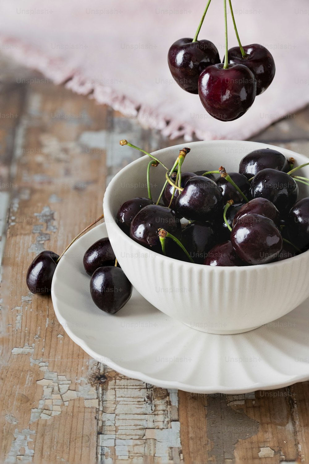 a white bowl filled with cherries on top of a wooden table