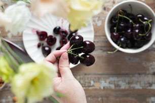 a person holding a bunch of cherries in front of a bowl of cherries