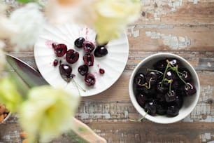 a bowl of cherries next to a plate of cherries