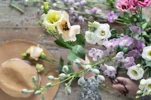 una persona sosteniendo un ramo de flores junto a un sombrero