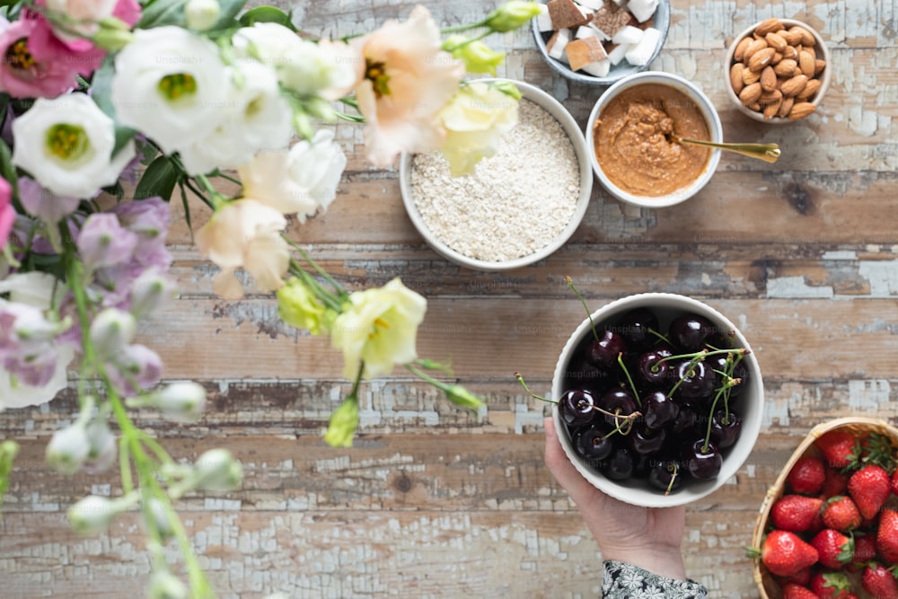 a person holding a bowl of berries and a bowl of nuts