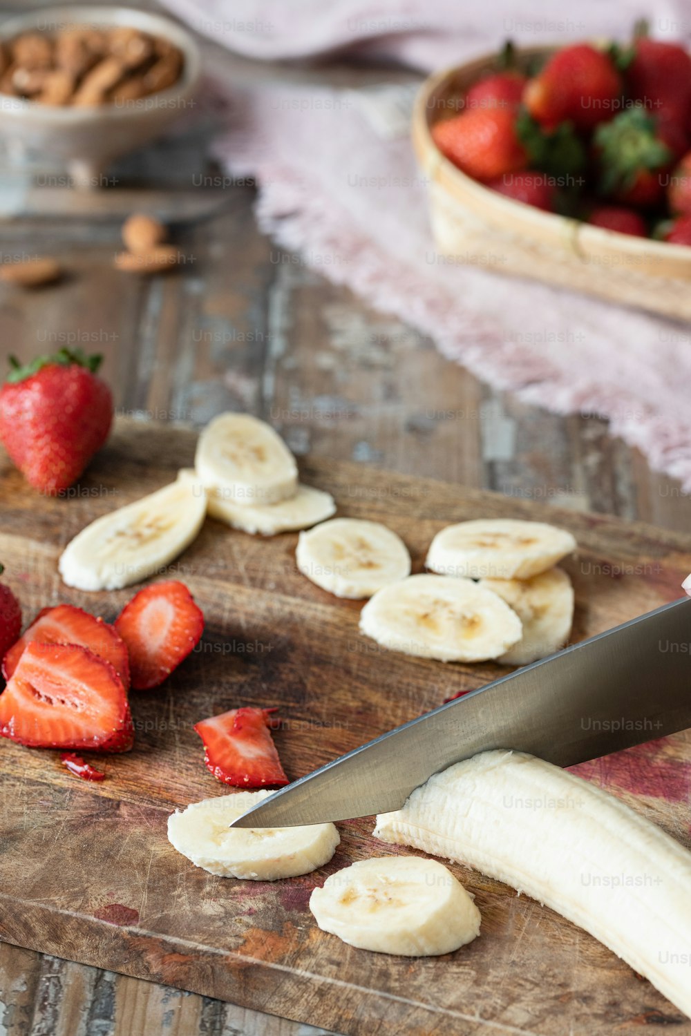 a cutting board topped with sliced bananas and strawberries