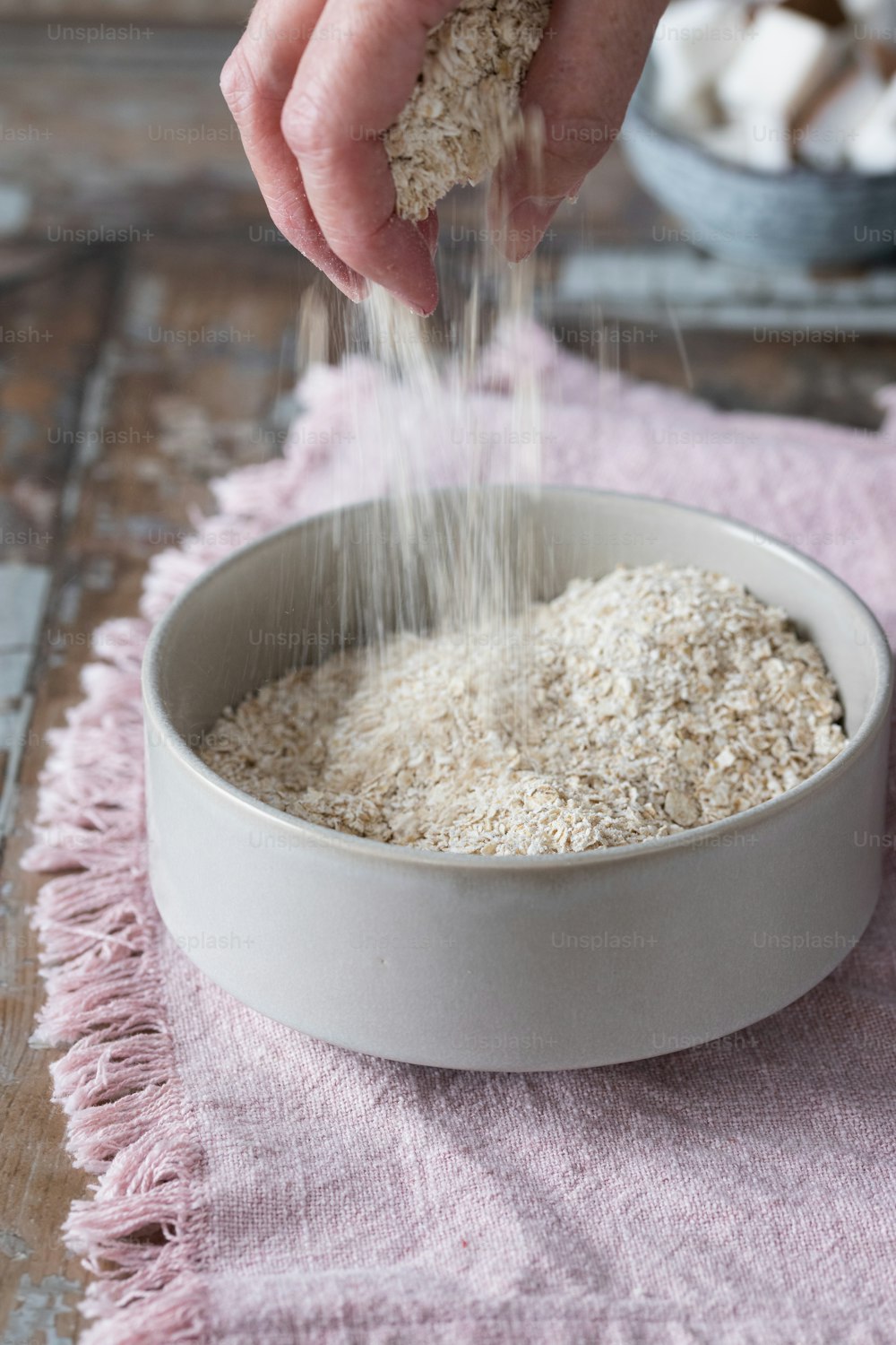 une personne saupoudre du riz dans un bol