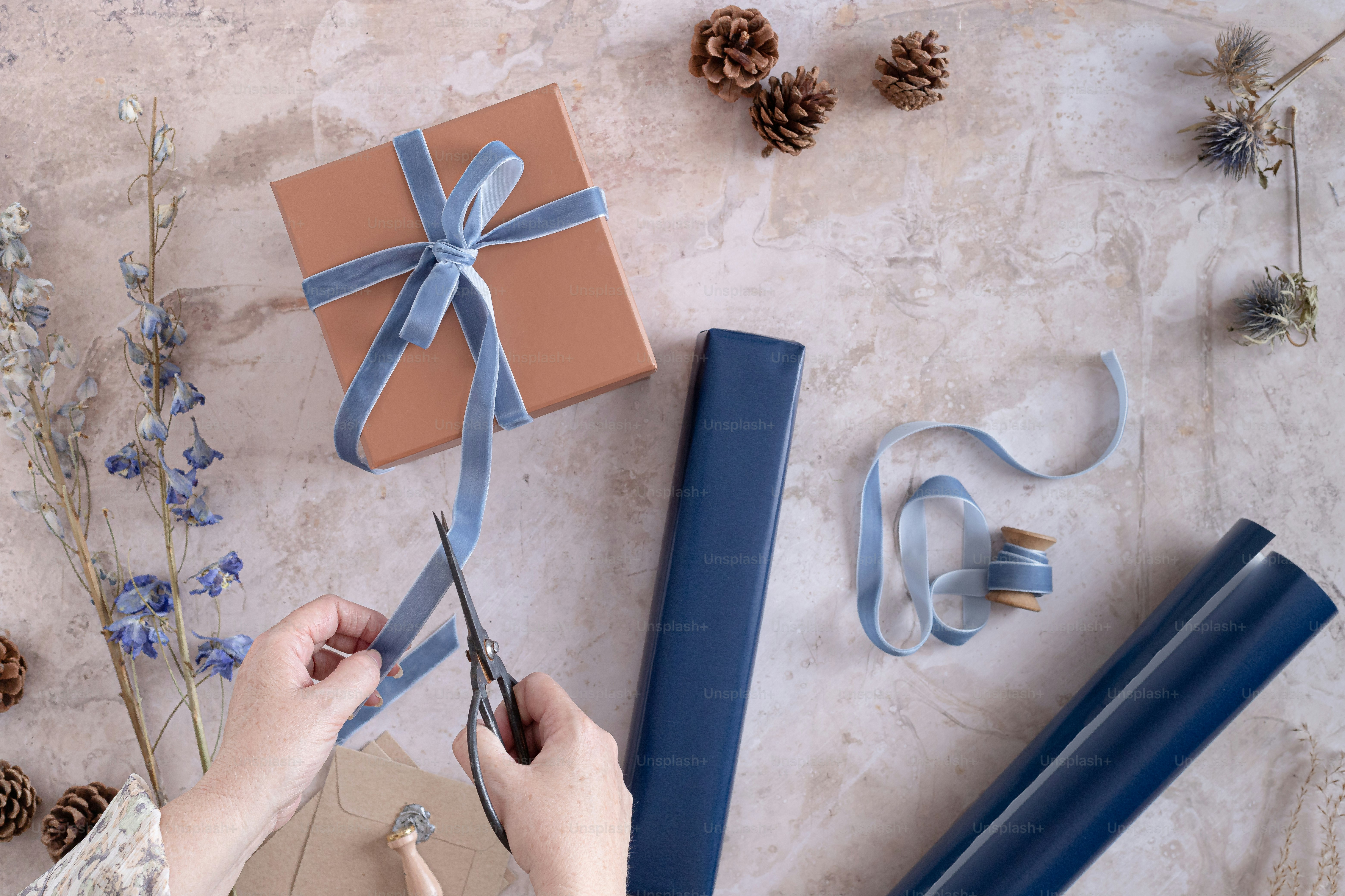 A person cutting a ribbon with scissors on a table photo Gift wrap