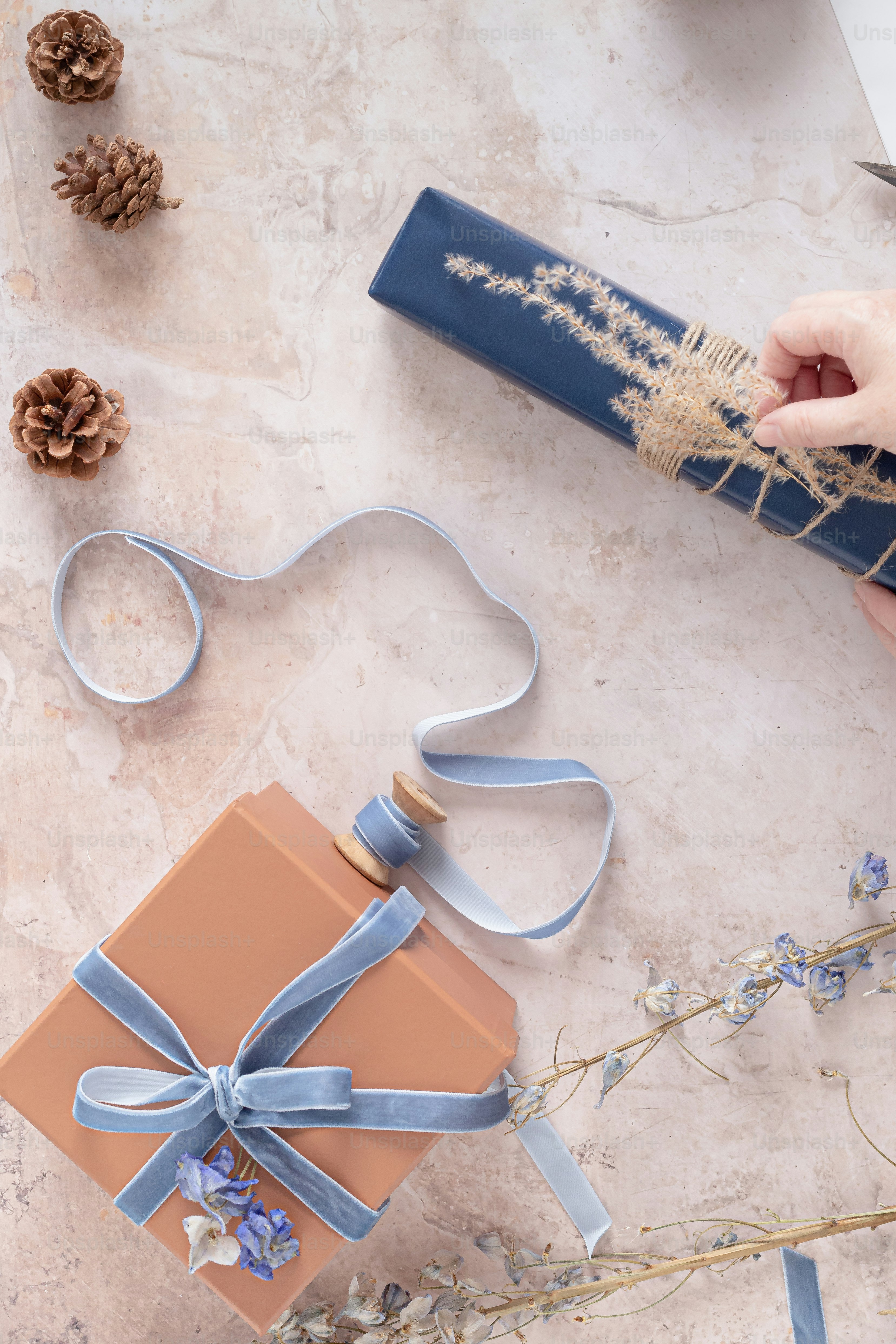 A person is wrapping a gift with a blue ribbon photo Presents Image