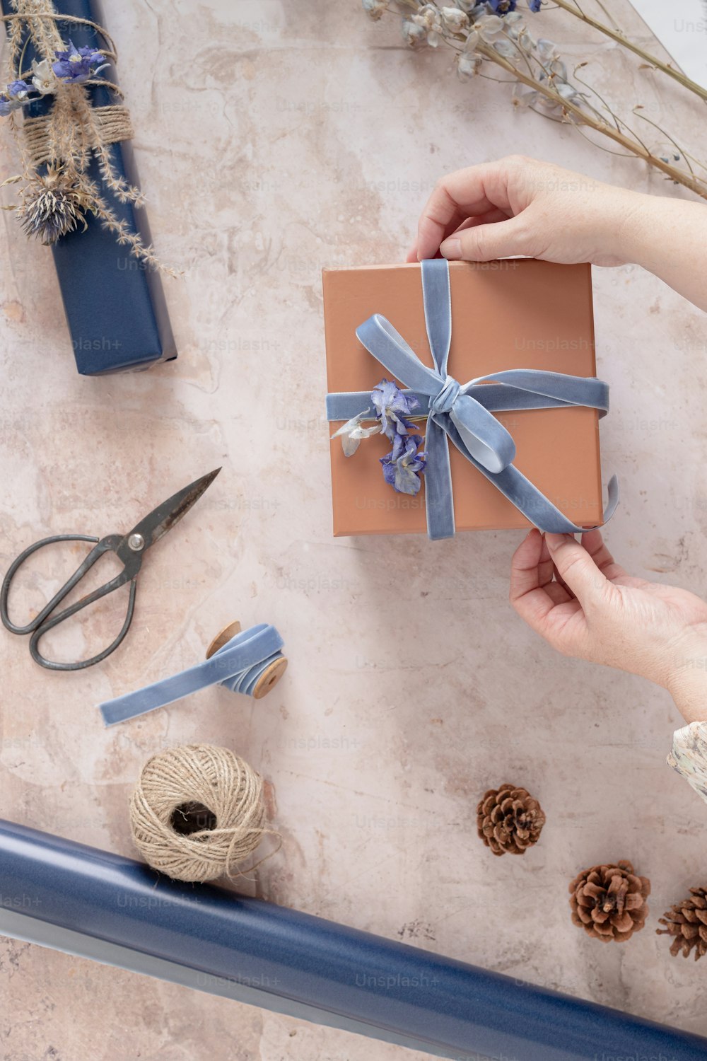 a person is wrapping a gift with a blue ribbon