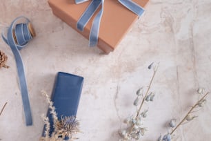 eine Geschenkbox mit einem blauen Band und einigen getrockneten Blumen