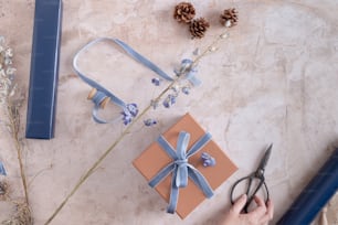 a person holding a pair of scissors next to a gift