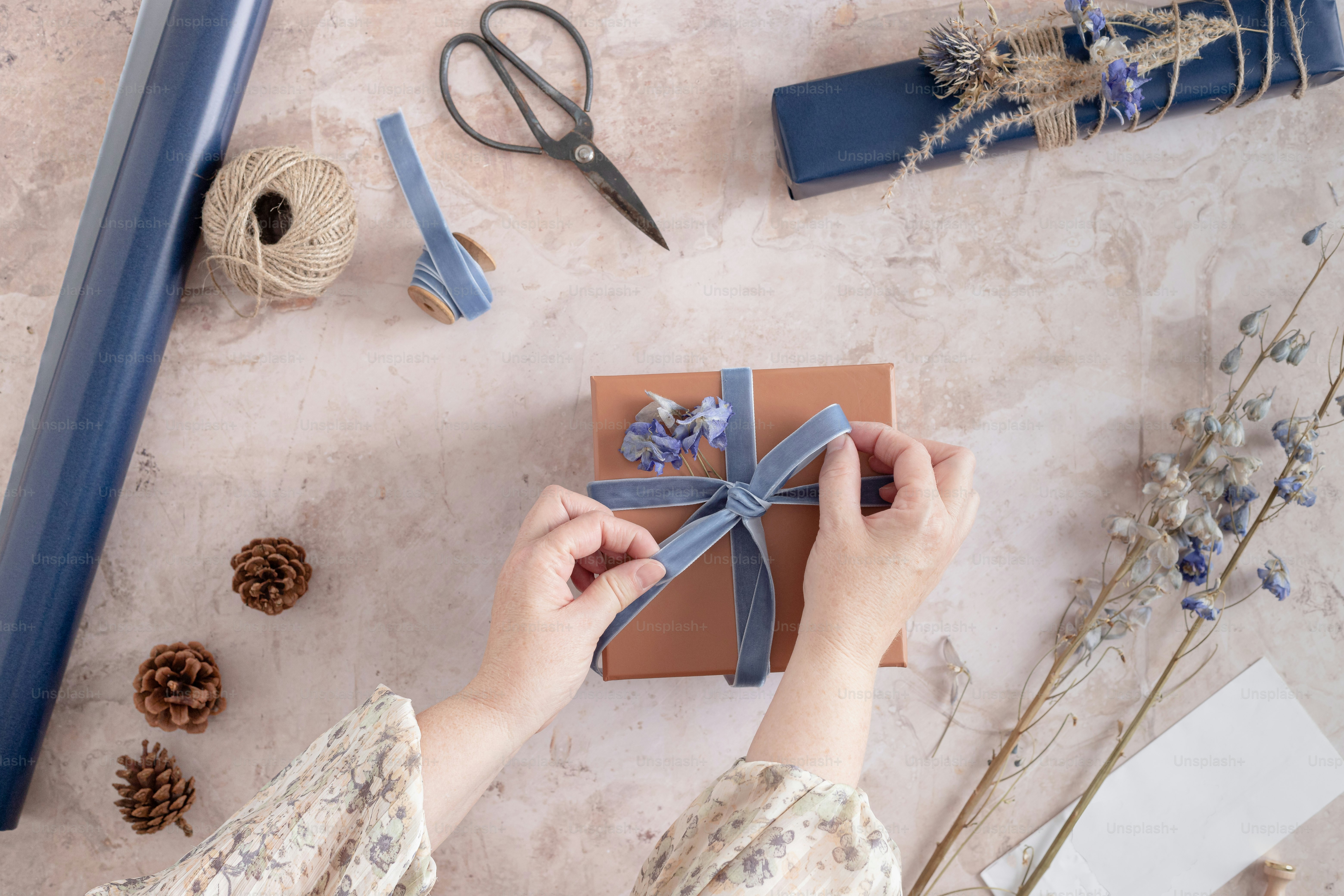 A woman is wrapping a gift with a blue ribbon photo Present Image on