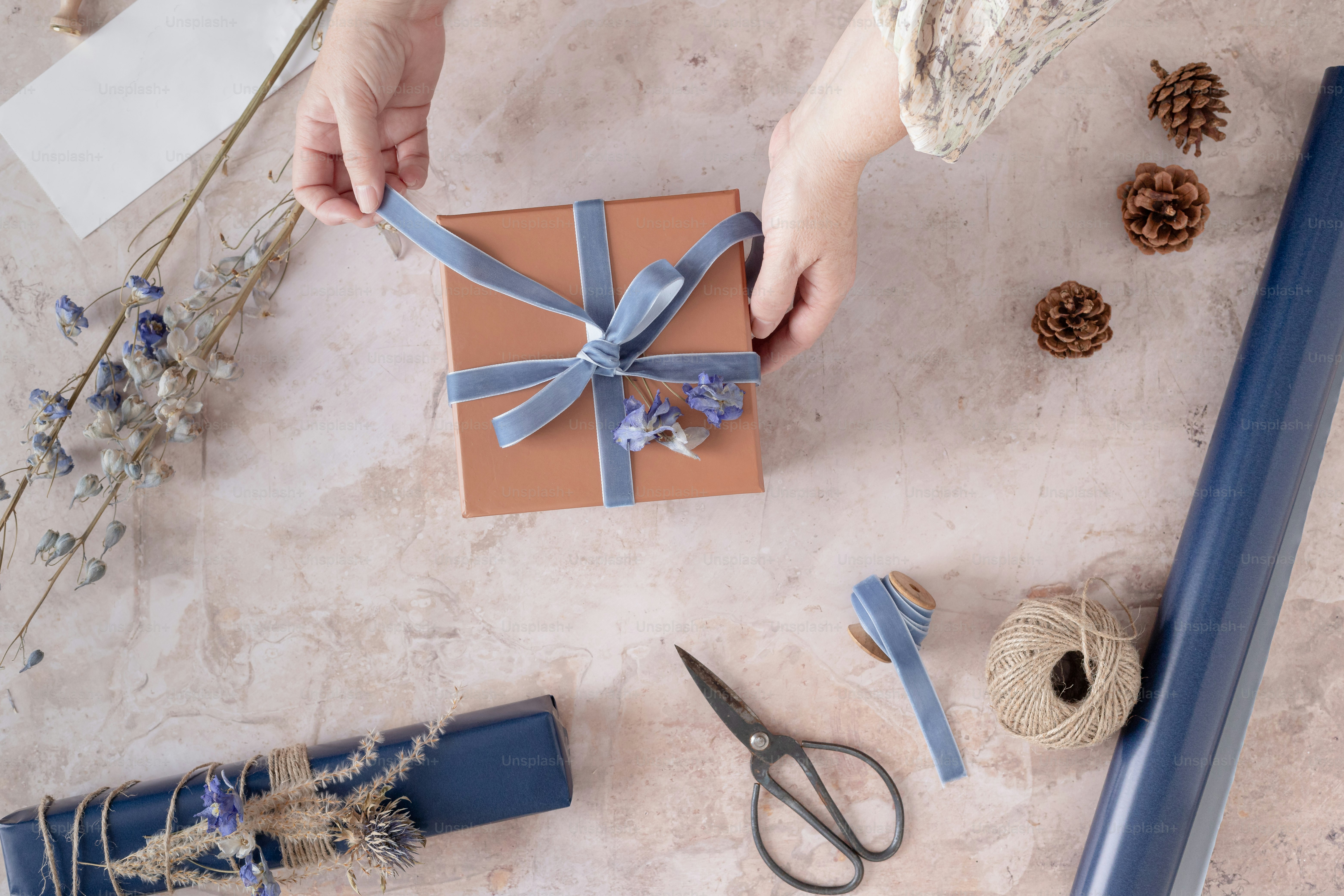 A woman is wrapping a gift with a blue ribbon photo Festive Image on