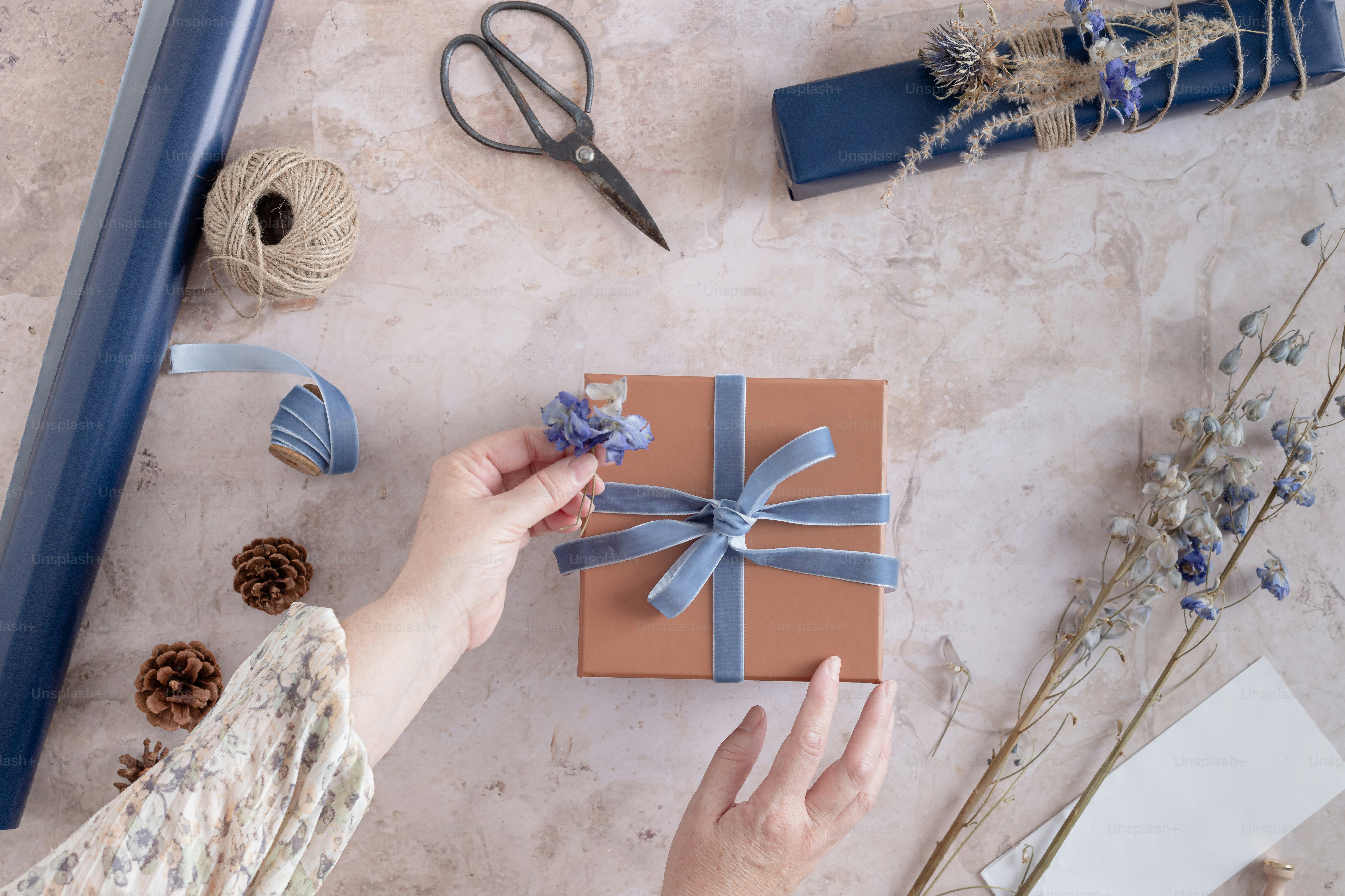 A woman is wrapping a gift with a blue ribbon photo Gift wrapping