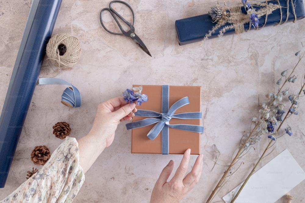 a woman is wrapping a gift with a blue ribbon