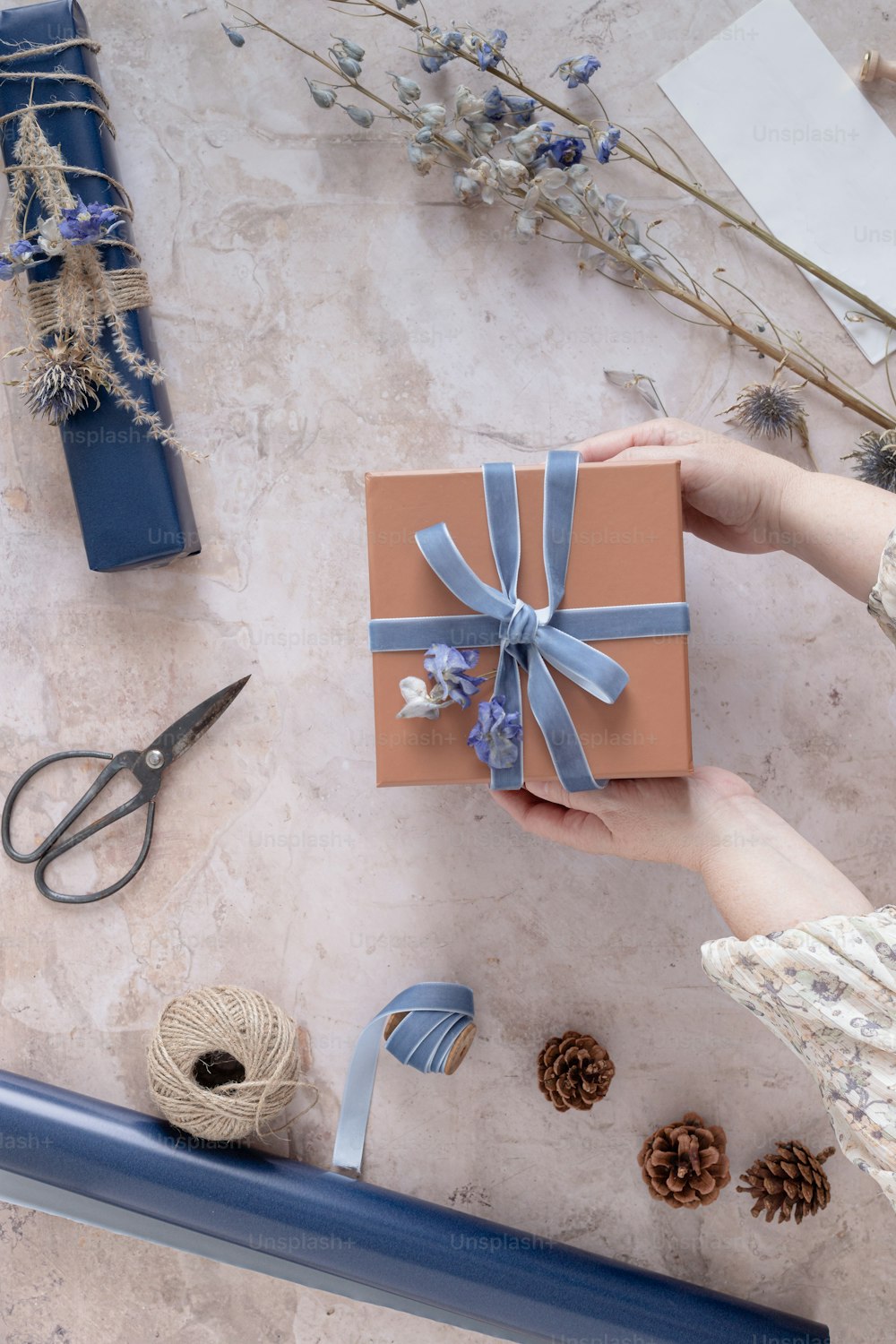 a woman holding a wrapped gift box with a blue ribbon