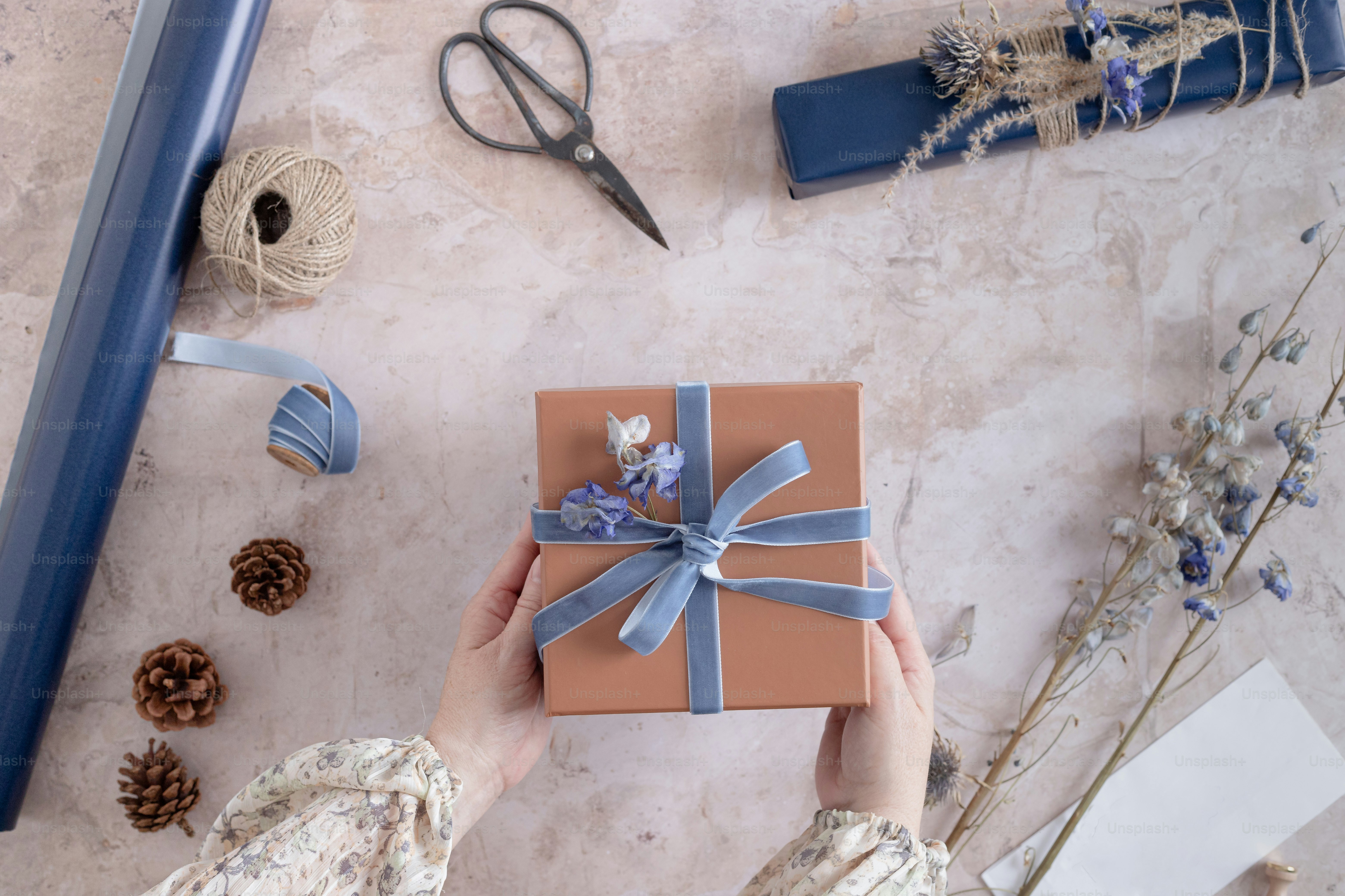 a woman holding a wrapped gift box with a blue ribbon