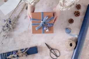 a woman holding a gift box with a blue ribbon