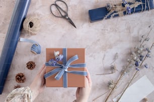 a person holding a gift box with a blue ribbon