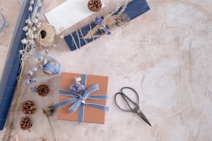un cadeau enveloppé dans un ruban bleu à côté d’une paire de ciseaux