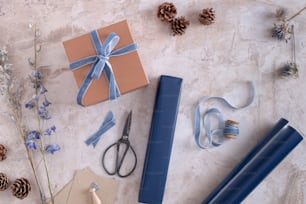 une table surmontée de papier d’emballage bleu et d’une paire de ciseaux