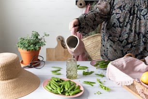 a woman pours a pitcher of water over a table filled with green beans